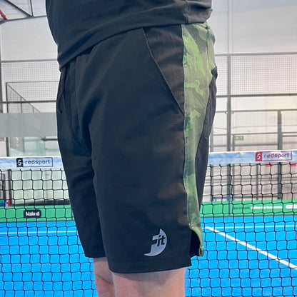 Black athletic shorts with green camouflage side panel on a padel court